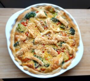 Homemade healthy quiche on a wooden plate ready to serve.