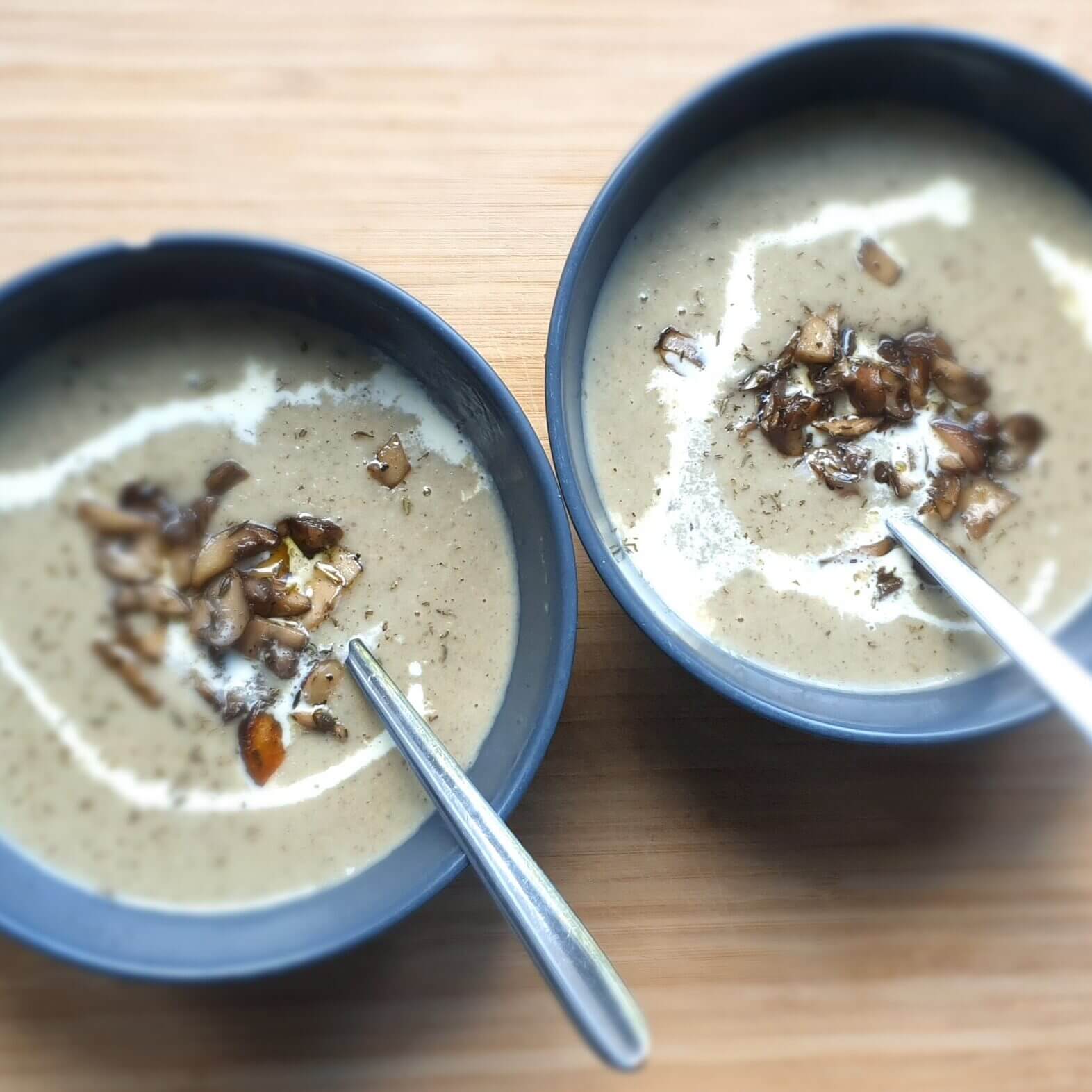 Homemade Creamy Mushroom Soup on a wooden plate in two bowls.