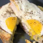 a croque madame sliced in half on a blue plate
