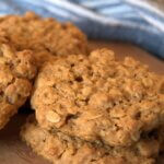 Peanut butter and oats cookies with a cloth in the background on a wooden plate.