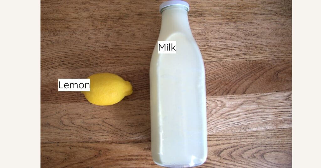 Overhead view of a whole lemon and a glass bottle of milk labeled with text, placed on a wooden surface.